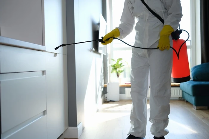 Person in hazmat suit spraying indoor pest control.